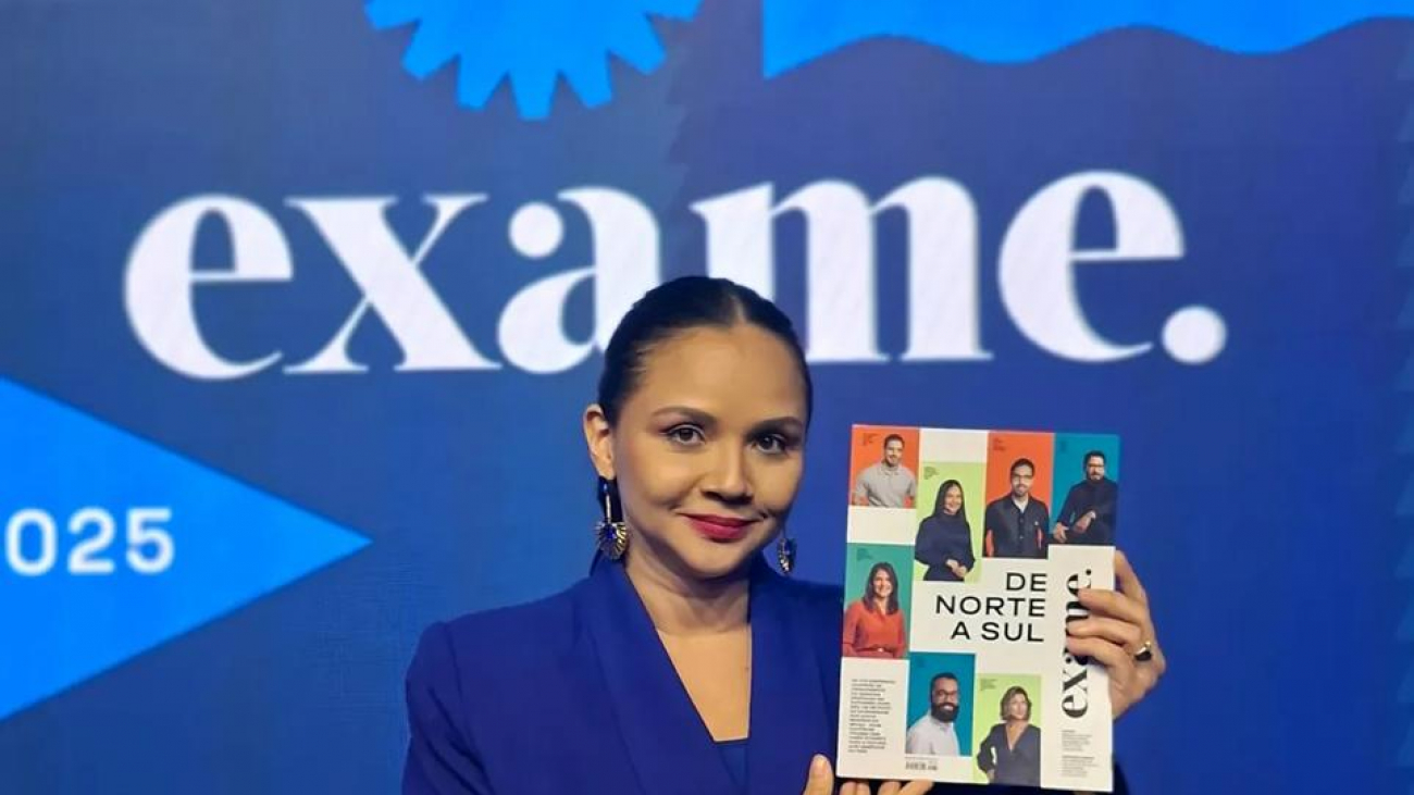 A imagem mostra Michelle Guimarães, CEO da Navegam, segurando a Revista da Exame em frente a um painel do ranking "Negócios em Expansão".