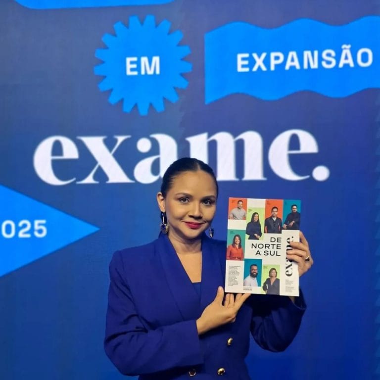 A imagem mostra Michelle Guimarães, CEO da Navegam, segurando a Revista da Exame em frente a um painel do ranking "Negócios em Expansão".