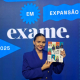 A imagem mostra Michelle Guimarães, CEO da Navegam, segurando a Revista da Exame em frente a um painel do ranking "Negócios em Expansão".